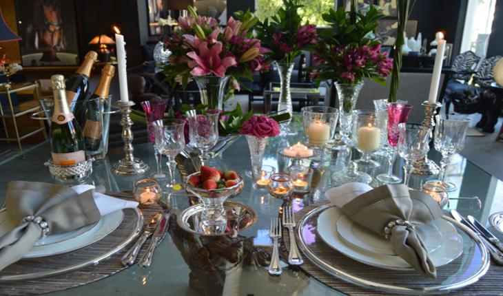 mesa decorada comflores em tons de rosa, guardanapo bege preso com miçangas, champagne, velas e taças