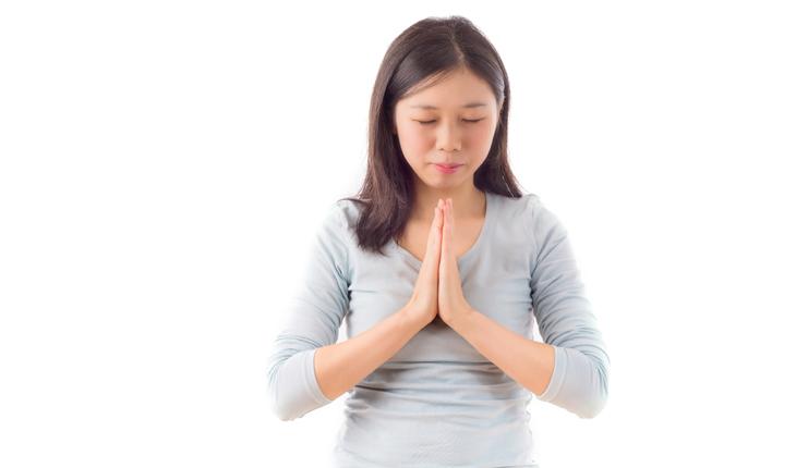 mulher com traços asiáticos rezando