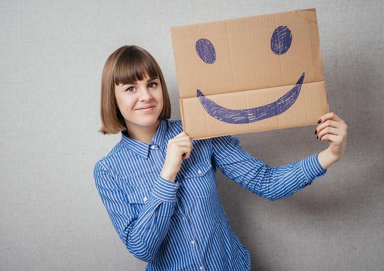 Mulher com um papel desenhado um ícone de sorriso
