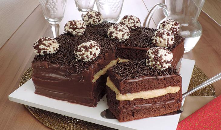 foto de bolo de chocolate com cobertura de brigadeiro, dois recheis (um branco e um preto) e bolinhas de brigadeiro decorando
