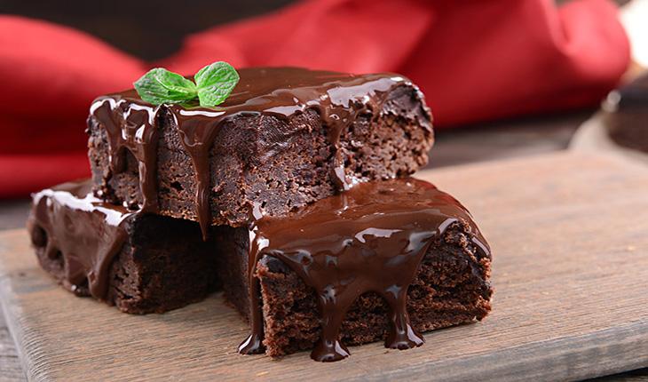 bolo molhadinho de chocolate, cortado em pedaços, com calda de chocolate e um raminho de hortelã decorando