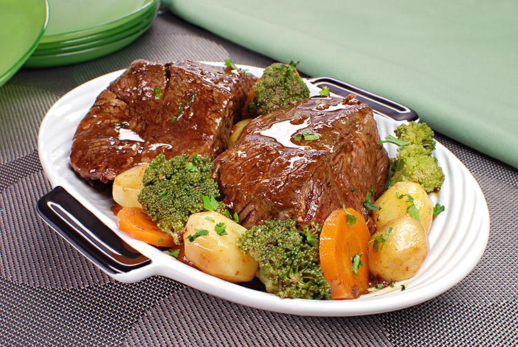 Carne bovina de panela na travessa com batata, cenoura e brócolis cozidos.