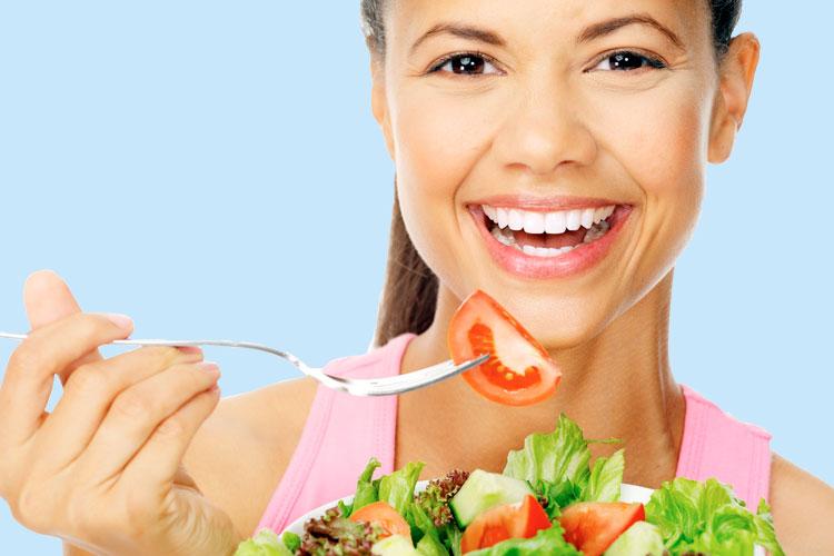 Mulher comendo salada e sorrindo