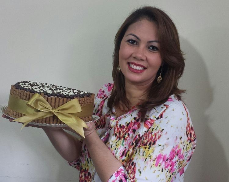 Foto de Aylla, dona da confeitaria Doceres segurando um bolo