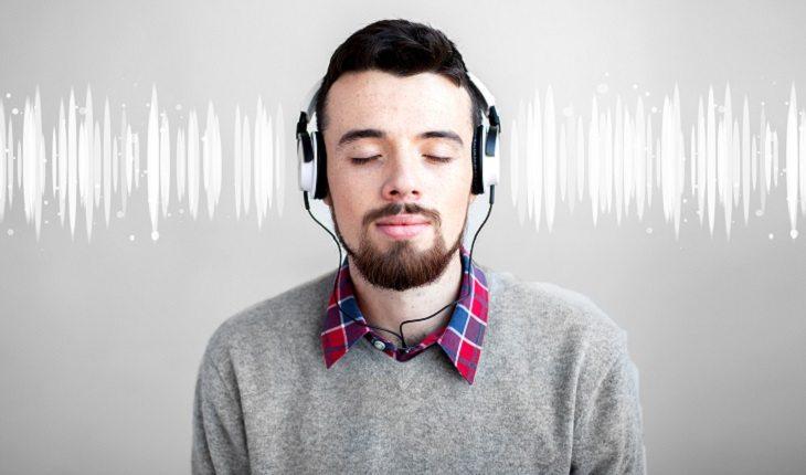 A foto mostra um homem escutando música com os olhos fechados
