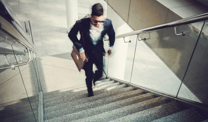 A foto mostra um homem subindo um lance de escadas correndo