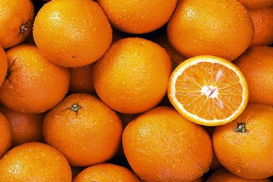 Várias laranjas juntas e uma delas cortada ao meio