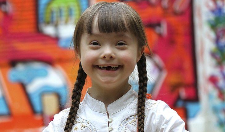A foto mostra uma menina com síndrome de Down vestindo uma roupa característica do Japão