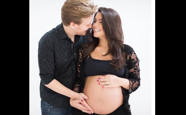 Michel e Thaís com roupas pretas e ela com barriga de fora em ensaio de gravidez