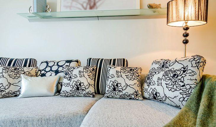 Sala com sofá claro com almofadas estampadas em preto e branco.