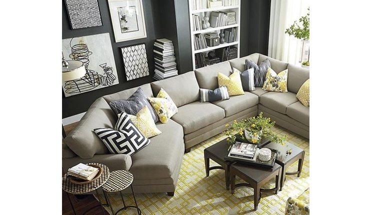 Sala com um sofá cinza e almofadas estampadas em preto e amarelo. O tapete também é amarelo com listras