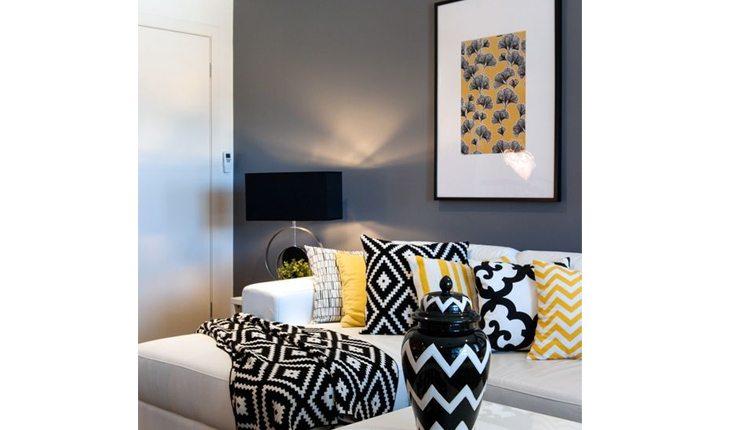 Sala com sofá claro e almofadas com estampas amarelas e pretas