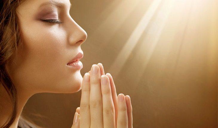 Mulher orando de olhos fechados pedindo auxílio pelo poder da fé