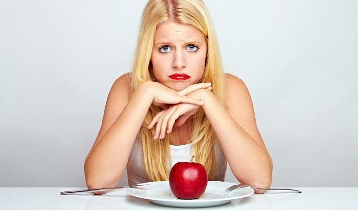 mulher triste comendo uma maçã