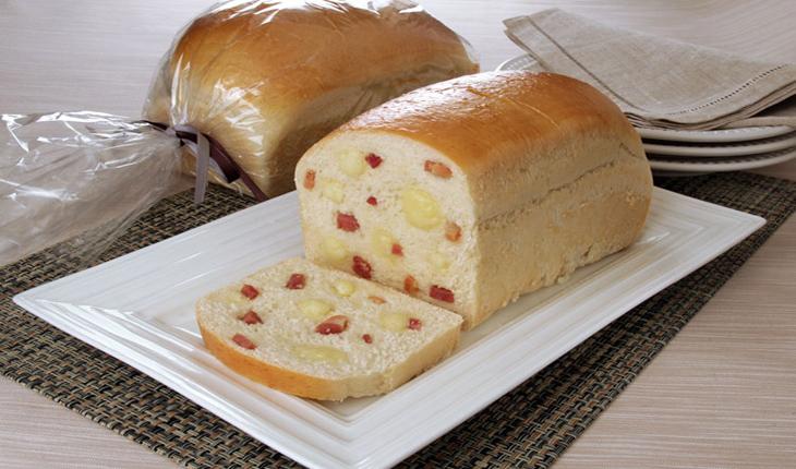 pão de queijo com calabresa servido em um prato branco e ainda dentro da embalagem ao fundo