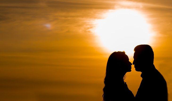 Matrimônio. Na foto, mulher e homem beijando no por do sol