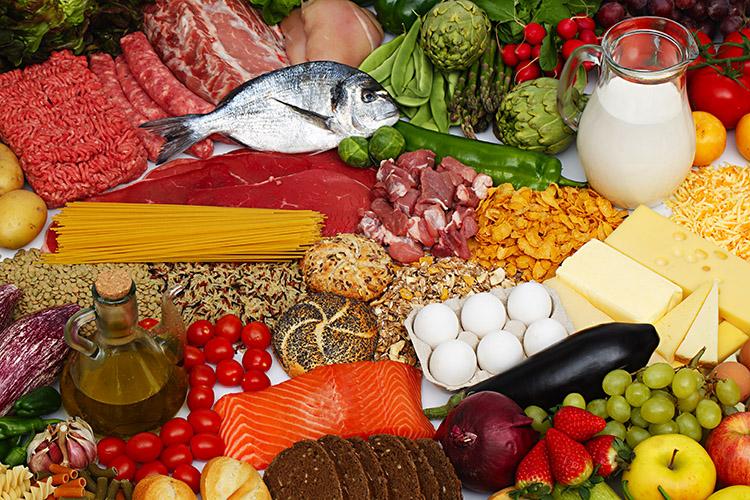 Diversos alimentos dispostos em uma mesa. Peixe, legumes, ovos, frutas e verduras.