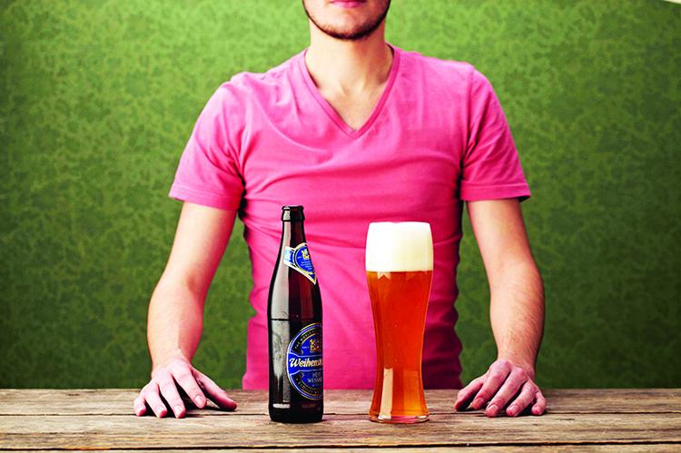 menino de camiseta rosa servindo em um copo a cerveja de trigo