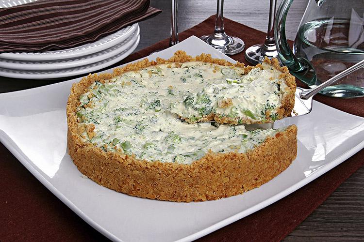 Torta de cream cheese e brócolis em um prato branco quadrado com um pedaço sendo retirado.