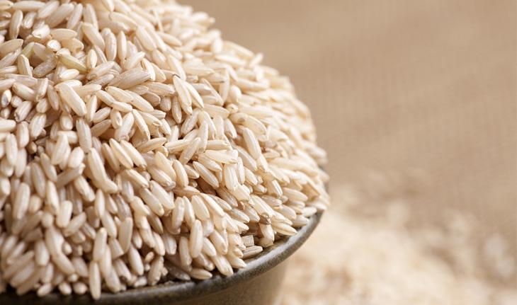 arroz integral dentro de um pote, ao fundo mais grãos do arroz