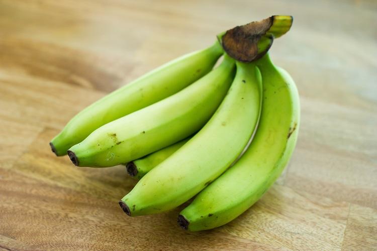 Bananas verdes, sobre a madeira