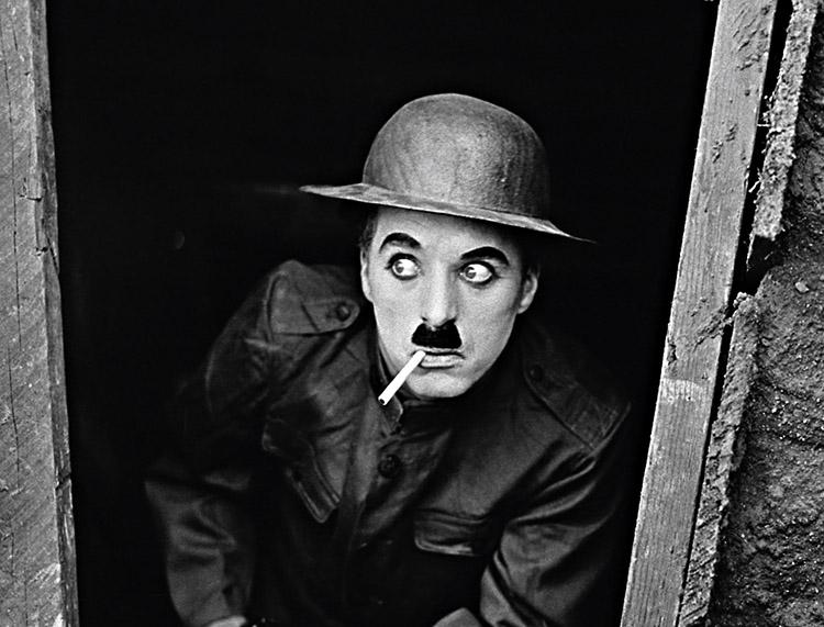 foto em preto e branco do ator Charles Chaplin com um cigarro em sua boca 