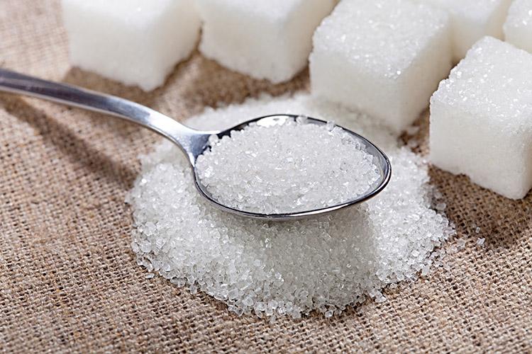 Quadradinhos de açúcar com uma colher cheia de açúcar. 