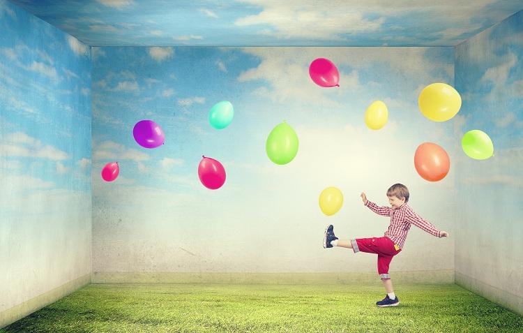 menino chutando balões coloridos