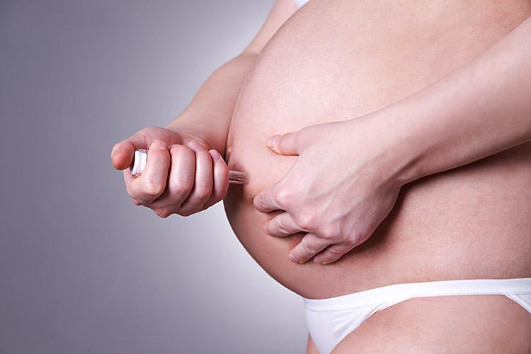 Mulher, grávida, aplicando injeção na barriga