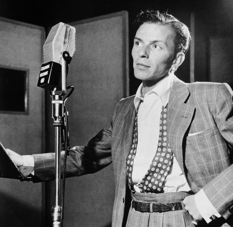 cantor Frank Sinatra com terno e um microfone