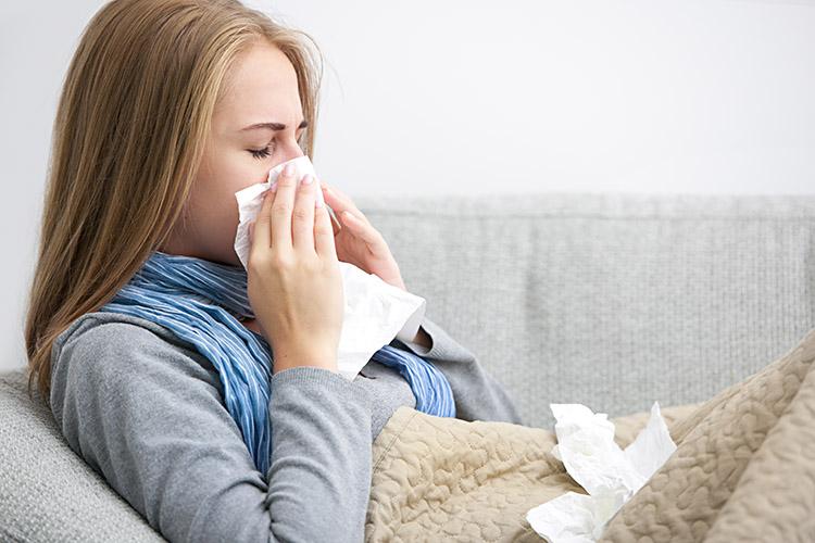 Mulher gripada assoando o nariz