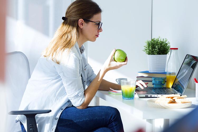 mulher comendo em frente ao computador