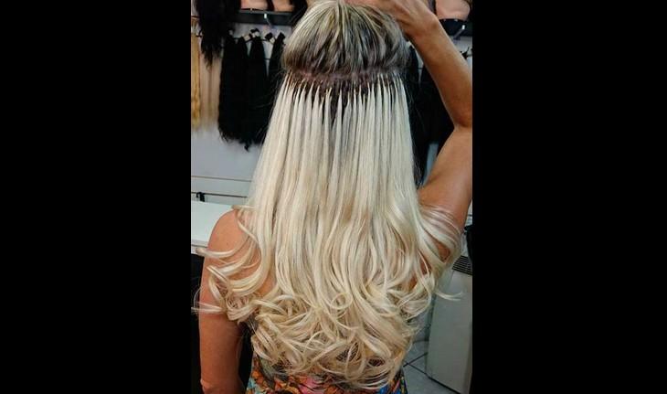 mulher levanta parte do cabelo para mostrar aplicação de megahair platinado