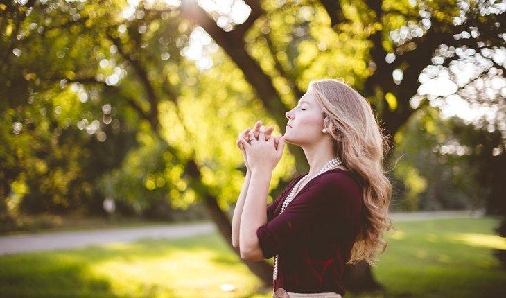 mulher rezando em meio à natureza