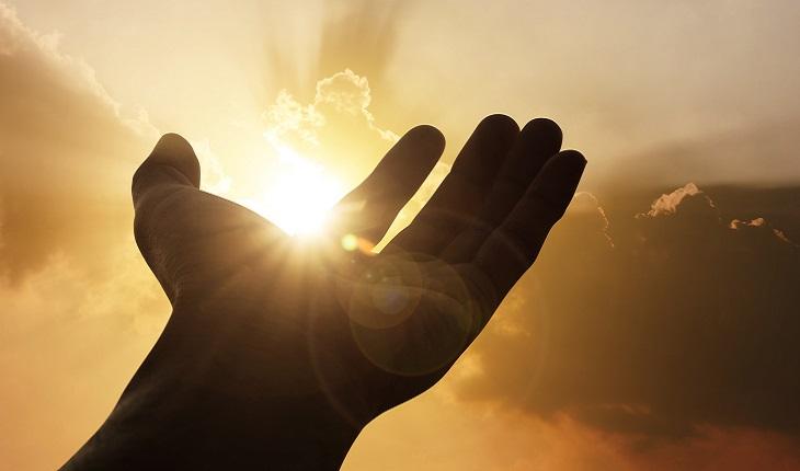 A foto mostra uma pessoa em sua rotina com a mão em direção ao sol