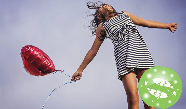 Na foto há uma mulher segurando um balão em formato de coração.