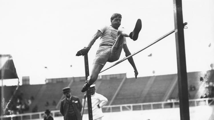 Ray Ewry realiza salto estático, modalidade hoje extinta, durante os Jogos de Londres 1908 