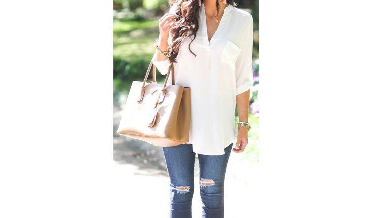 mulher de aclça jeans, camisa branca segurando uma bolsa grande marrom