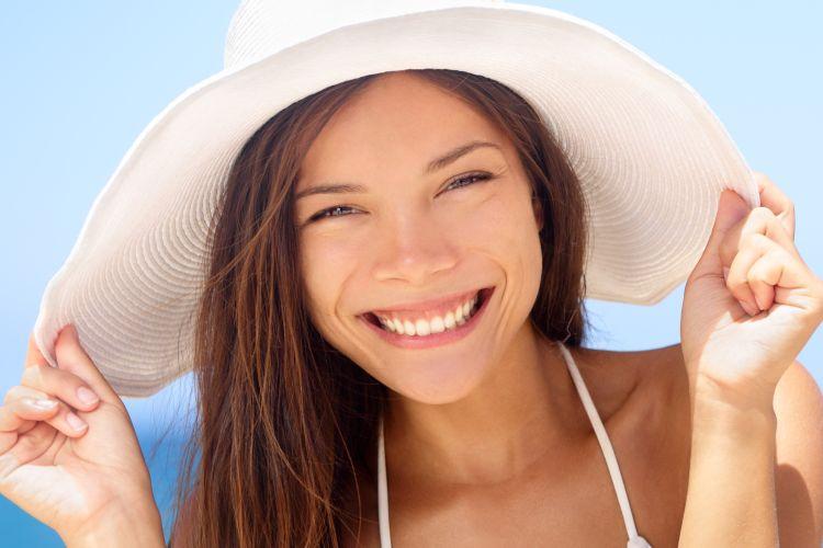 Mulher proteger cabelo com chapéu na praia