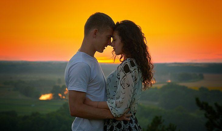 casal se abraçando durante o pôr do sol em um campo aberto