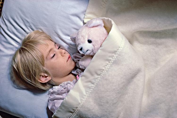 criança dormindo abraçada com urso de pelúcia