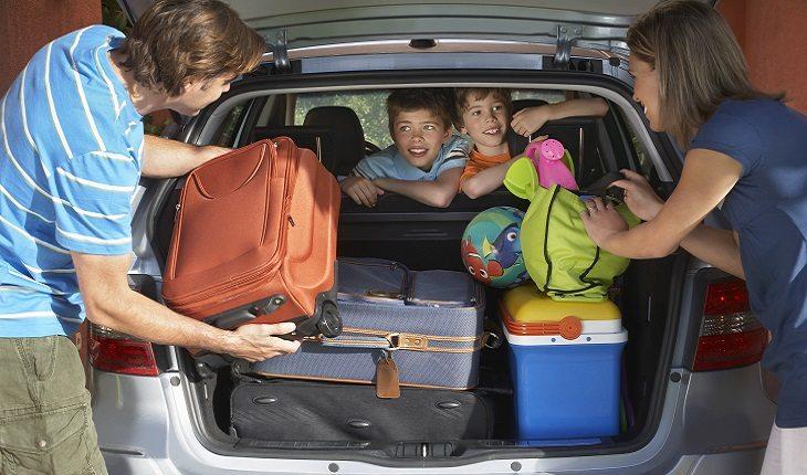 família colocando malas no carro para viajar