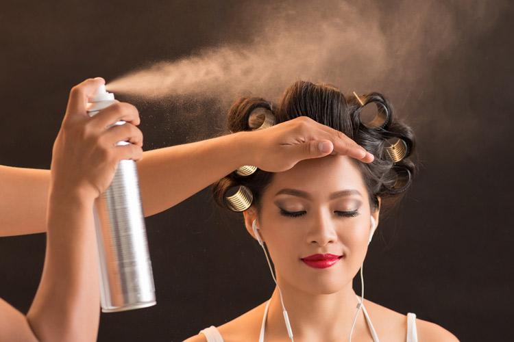 mulher espirrando finalizadores nos cabelos