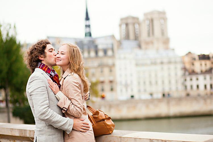 homem beijando o rosto de uma mulher enquanto estão abraçados na rua de uma cidade
