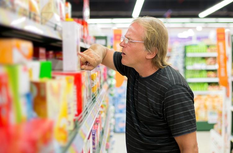 homem lendo rótulo de produto em supermercado