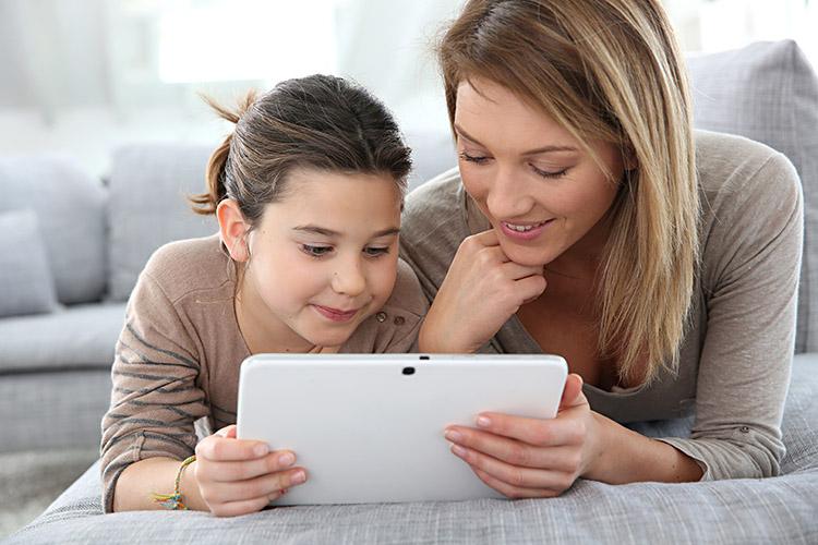 Mãe ensinando filha a usar tablet