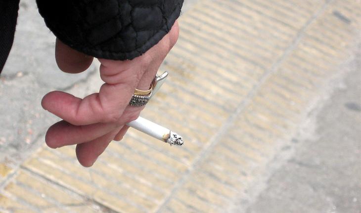 Mão feminina segurando um cigarro aceso