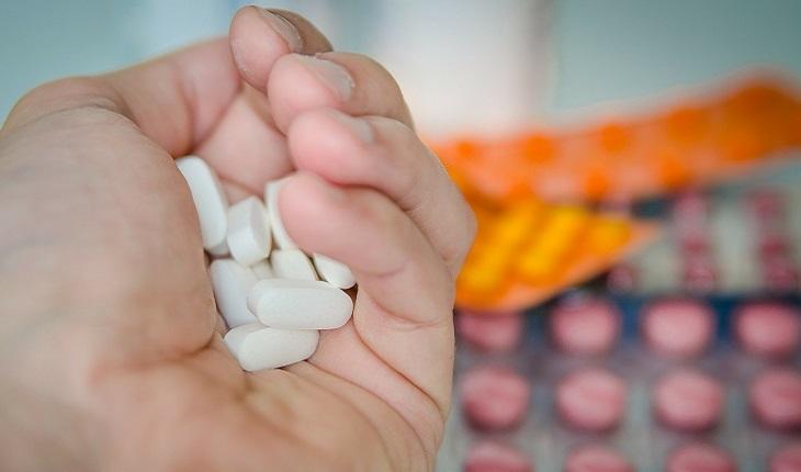 A foto mostra uma mão segurando comprimidos que não pertencem à homeopatia