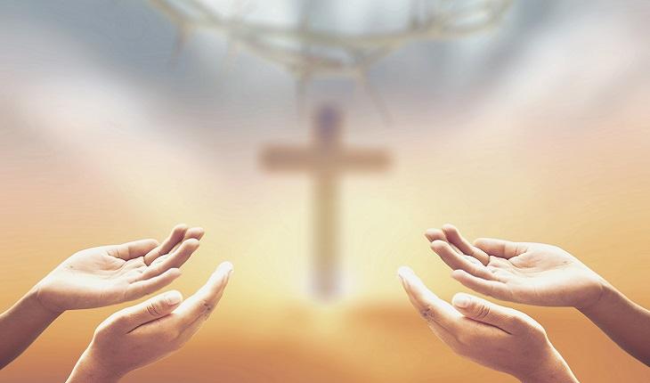 A foto mostra duas pessoas apontando as mãos abertas para o céu com uma cruz, como se fosse o início de um exorcismo