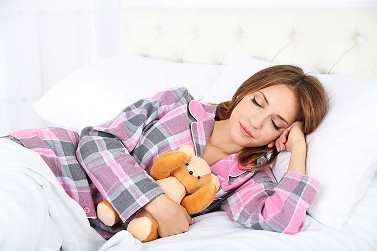 mulher pijama deitada cama ursinho pelucia sono